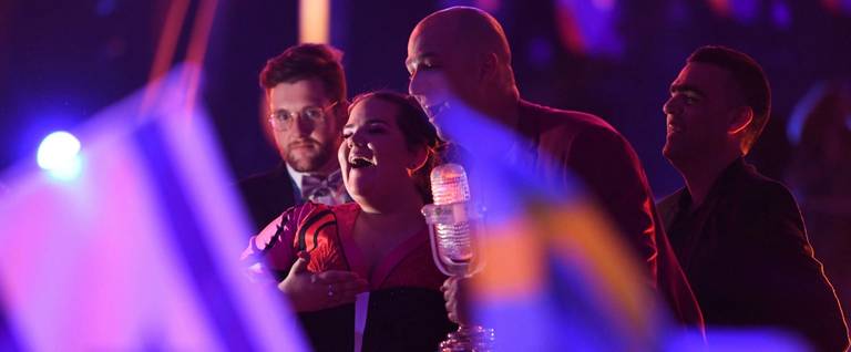 Israel's singer Netta Barzilai aka Netta celebrates with the trophy next to an Israel's flag after winning the final of the 63rd edition of the Eurovision Song Contest 2018 at the Altice Arena in Lisbon, on May 12, 2018.