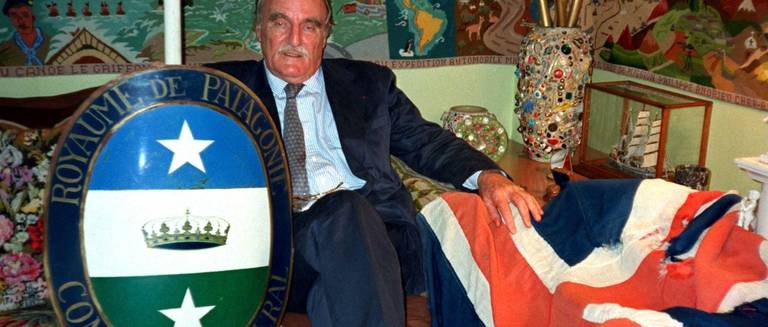 French writer Jean Raspail, the self-declared consul of the 'Kingdom of Patagonia', poses with Patagonia's coat of arms (L) and the British flag he seized on British rocks in the Channel September 1, 1998. Friends of Raspail hoisted Patagonia's flag in place of the Union Jack on August 30th over the Minquiers, a deserted series of rocks south of the Channel island of Jersey. Raspail offered to return the British flag but said the handover must be on neutral ground, a Paris bar. 