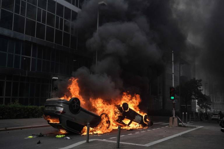  An overturned car burns during clashes between French police forces and youths after a memorial march for French teenager Nahel Merzouk, shot by police during a traffic control stop in Nanterre, France, on June 29, 2023