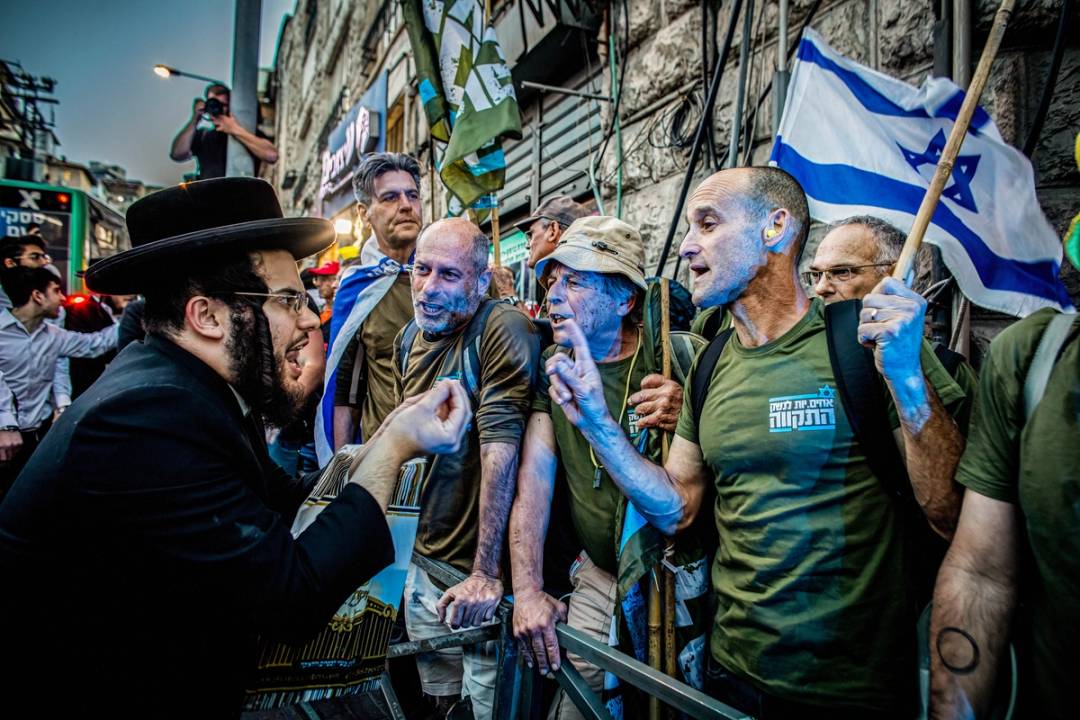 Ultra-orthodox Jewish youth argues with protesters during a demonstration in Jerusalem, March 31, 2024. Dozens of protesters from the Brothers in Arms movement staged a demonstration inside Jerusalem's ultra-Orthodox Mea Shearim neighborhood, calling for the community to be drafted to the Israel Defense Forces (IDF). 