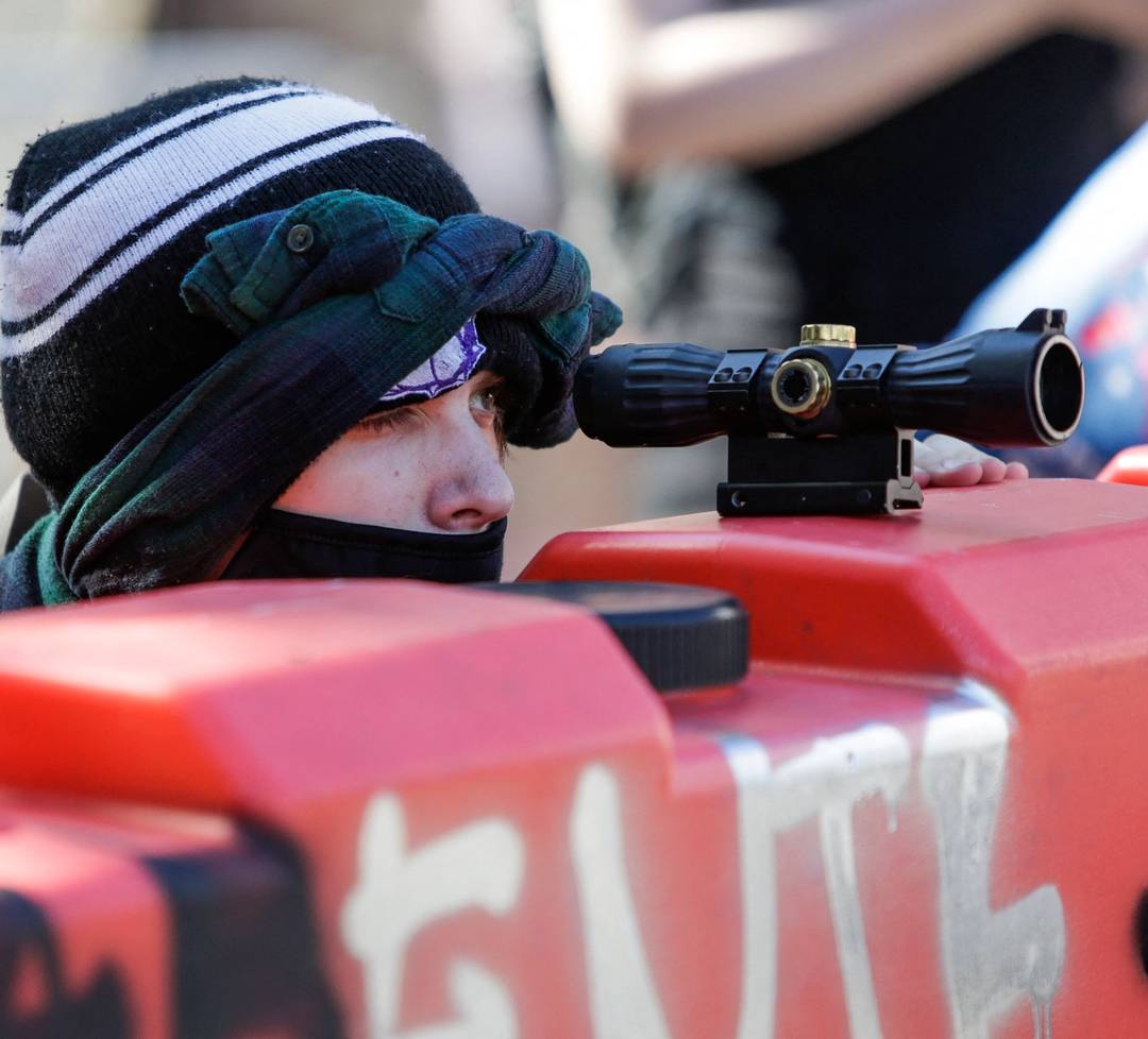 A protester uses a scope on top of a barricade to look for police approaching the Capitol Hill autonomous zone (CHAZ) in Seattle on June 11, 2020
