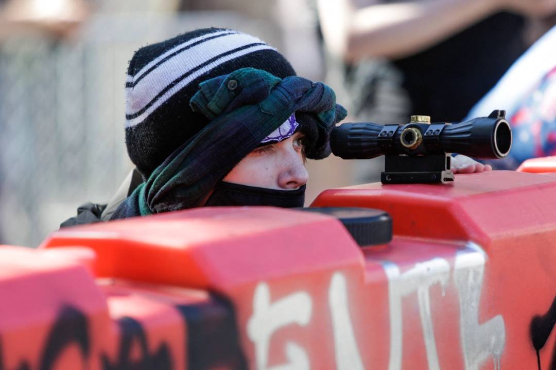 A protester uses a scope on top of a barricade to look for police approaching the Capitol Hill autonomous zone (CHAZ) in Seattle on June 11, 2020