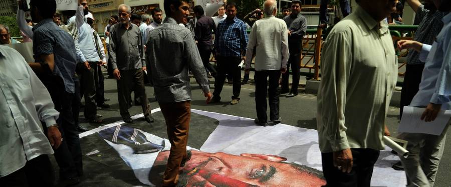 Iranians walk over an illustration of Barack Obama during a demonstration in Tehran, May 29, 2015. 