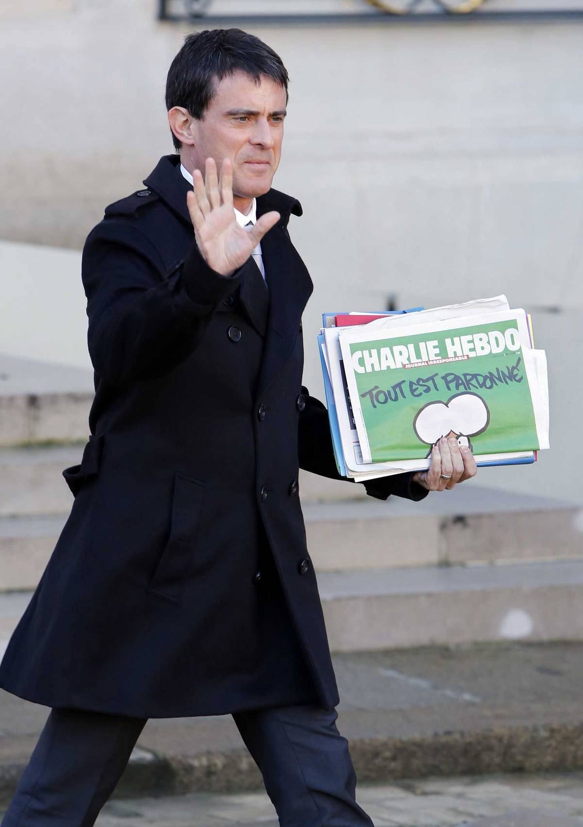 Valls, holding the latest edition of ‘Charlie Hebdo,’ leaves the Élysée Palace, Jan. 14, 2015