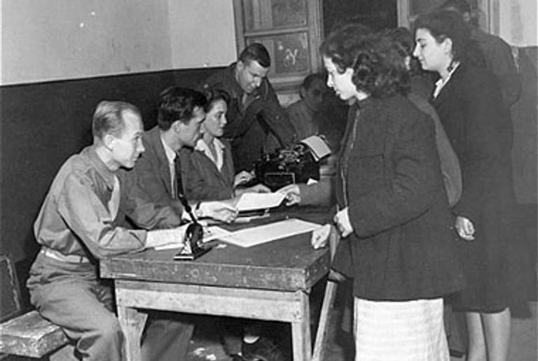 Jewish DPs en route to Palestine register in Rome on October 27, 1945. Among those pictured are Eugene Hammond, representative of the Intergovernmental Commission on Refugees, and Major George Hartman, Allied Commission Repatriation Officer.(United States Holocaust Memorial Museum, courtesy of National Archives and Records Administration, College Park)