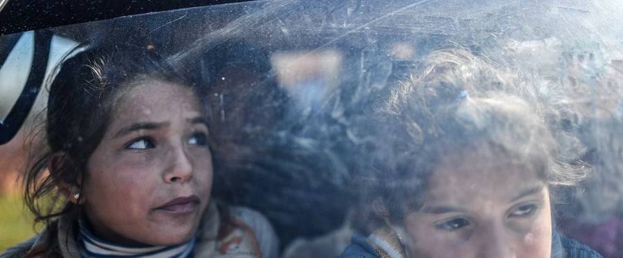 Syrian children look on as they arrive at a check point in the village of Anab ahead of crossing to the Turkish-backed Syrian rebels side on March 17, 2018, as civilians flee the city of Afrin in northern Syria. More than 200,000 civilians have fled the city of Afrin in northern Syria in less than three days to escape a Turkish-led military offensive against a Kurdish militia, a war monitor said on March 17. Turkey and its Syrian Arab rebel allies have waged a nearly two-month offensive on the Afrin enclave, which is held by the Kurdish People's Protection Units (YPG).