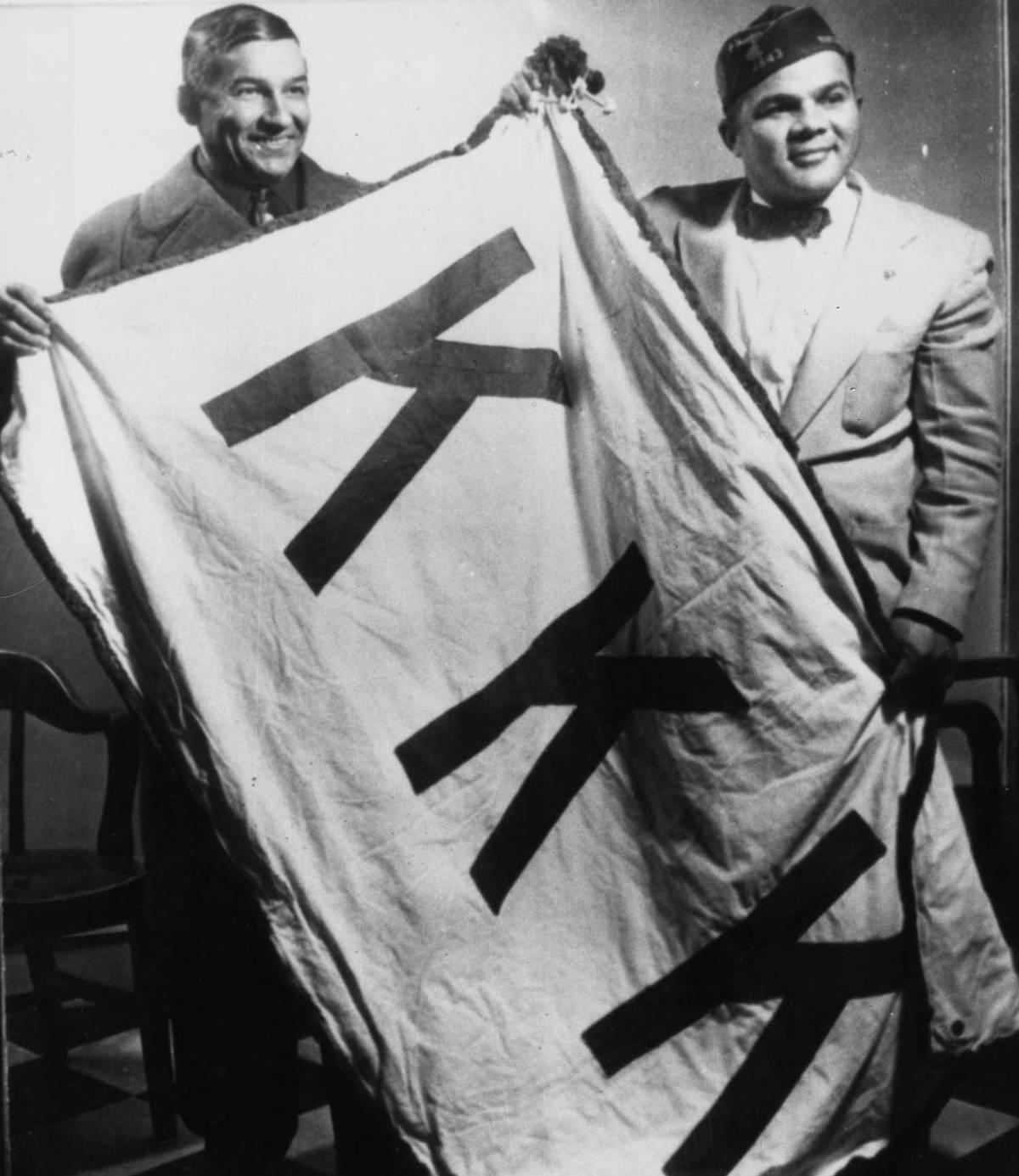 Lumbee members Charlie Warriax and Simeon Oxendine display a captured Ku Klux Klan banner which they confiscated after a raid on a Klan rally in Lumberton, North Carolina, 1958