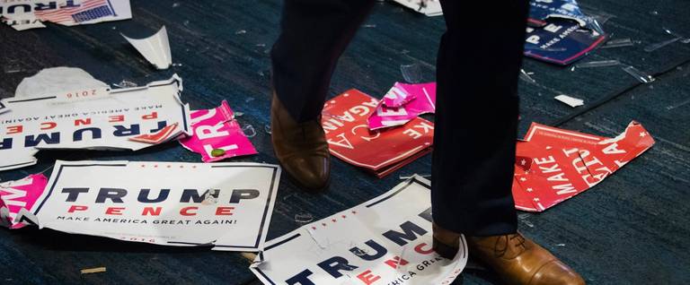 A supporter steps over placards that litter the floor of the ballroom where Republican presidential elect Donald Trump spoke during election night at the New York Hilton Midtown Manhattan, November 9, 2016. 