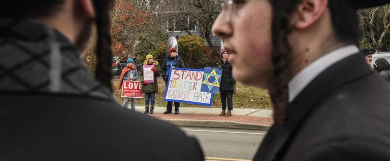 People hold signs of support near the house of Rabbi Chaim Rottenberg on Dec. 29, 2019, in Monsey, New York 