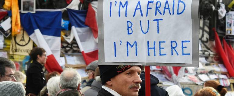 A man holds a placard reading during a gathering at Place de la République in Paris to mark the one-year anniversary since the attacks at 'Charlie Hebdo' and the Hyper Cacher kosher supermarket, January 10, 2016. 