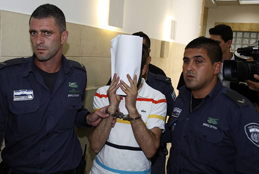 The 29-year-old Israeli prime suspect, who was charged along with two minors with the abduction and murder of the Palestinian teenager Mohammed Abu Khdeir, covers his face as he leaves the courtroom on July 17, 2014 at the Jerusalem district court. (GALI TIBBON/AFP/Getty Images)