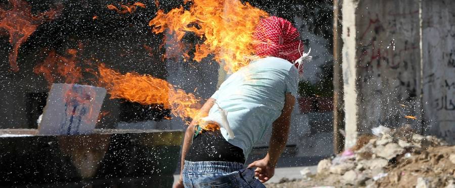 A Palestinian student throwing a Molotov cocktail towards Israeli soldiers and border police in the Hebron, October 13, 2015. 