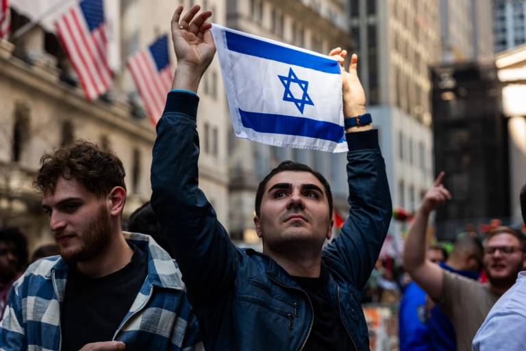 A man holds up an Israeli flag as pro-Palestinian protesters confront a small group of pro-Israel demonstrators during dueling events outside of the New York Stock Exchange on April 15, 2024