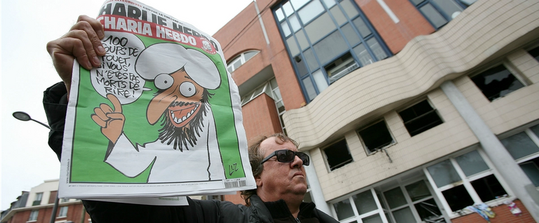 A man shows the French satirical magazine 'Charlie Hebdo,' featuring a caricature of the Prophet Muhammad on its cover, following a petrol bomb attack on the magazine's offices on Nov. 2, 2011, in Paris.