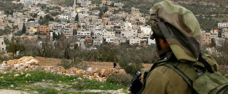 An Israeli soldier looks toward Palestinian protesters during clashes in the West Bank village of Madama, near the Jewish community of Yitzhar.