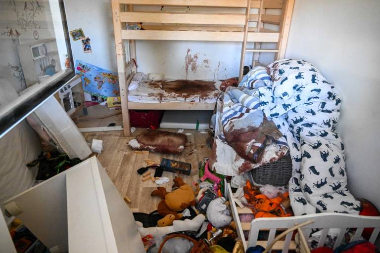 Large pools of blood stain a child's bunk bed and sheets inside a safe room, as seen through the window on Oct. 19, 2023, after Hamas militants days earlier attacked this kibbutz in Nir Oz, Israel, near the border of Gaza