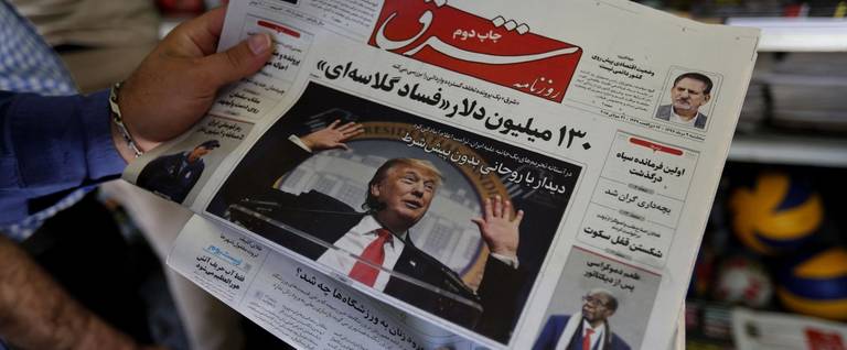 A man in Tehran glances at a newspaper with a picture of U.S. President Donald Trump on the front page, on July 31, 2018. 