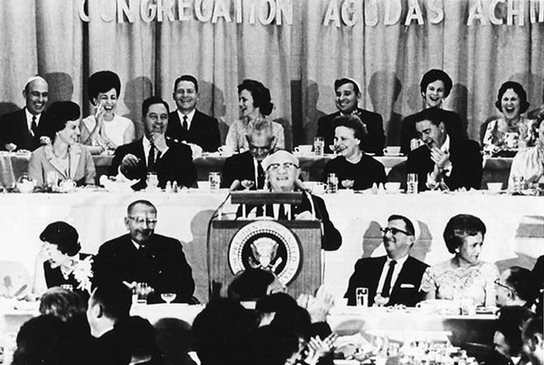 Jim Novy introduces President Lyndon Johnson at the dedication of Congregation Agudas Achim’s new building on Dec 28, 1963. Johnson and Lady Bird are seated to the left of the dais.