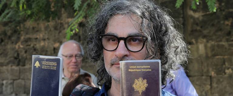 French-Lebanese director Ziad Doueiri, who has been criticised for filming part of a production in Israel, holds up his French and Lebanese passports outside the Military Tribunal in Beirut on September 11, 2017, after he was detained at Beirut airport on his way back from the Venice Film Festival.