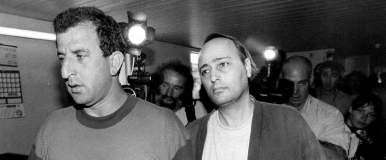 Eddie Antar (R), once known as 'Crazy Eddie,' New York's electronics king, is led by an Israeli police detective for a remand hearing after his arrest, June 25, 1992. 