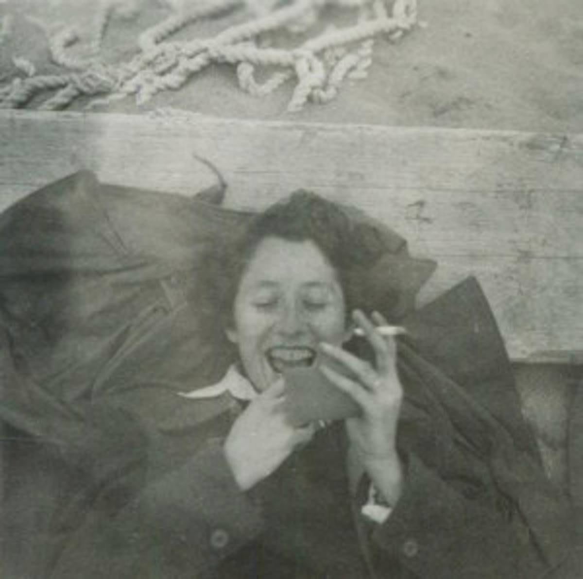 The author’s mother fixing her lipstick and smoking a cigarette on Nahariya beach, 1949.