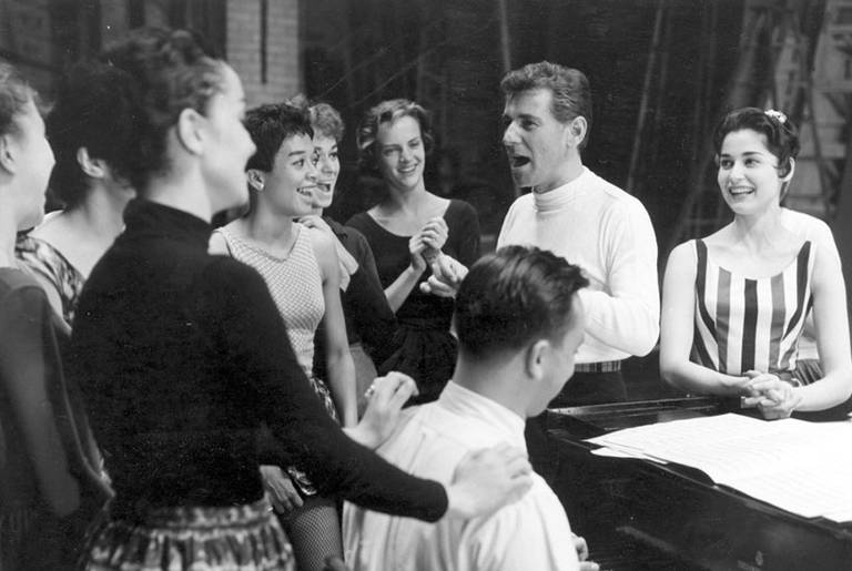 Bernstein at rehearsal for West Side Story. Carol Lawrence (who played Maria) is at his left, and lyricist Stephen Sondheim is playing the piano, 1957.(Library of Congress)