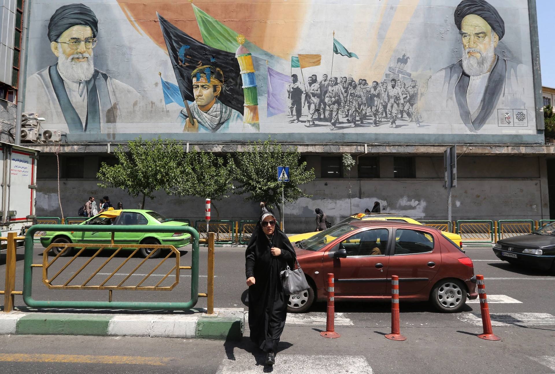 A woman walks past a mural painting depicting the late founder of the Islamic Revolution, Ayatollah Khomeini, and Iran's Supreme Leader Ayatollah Khamenei, in Tehran, 2019