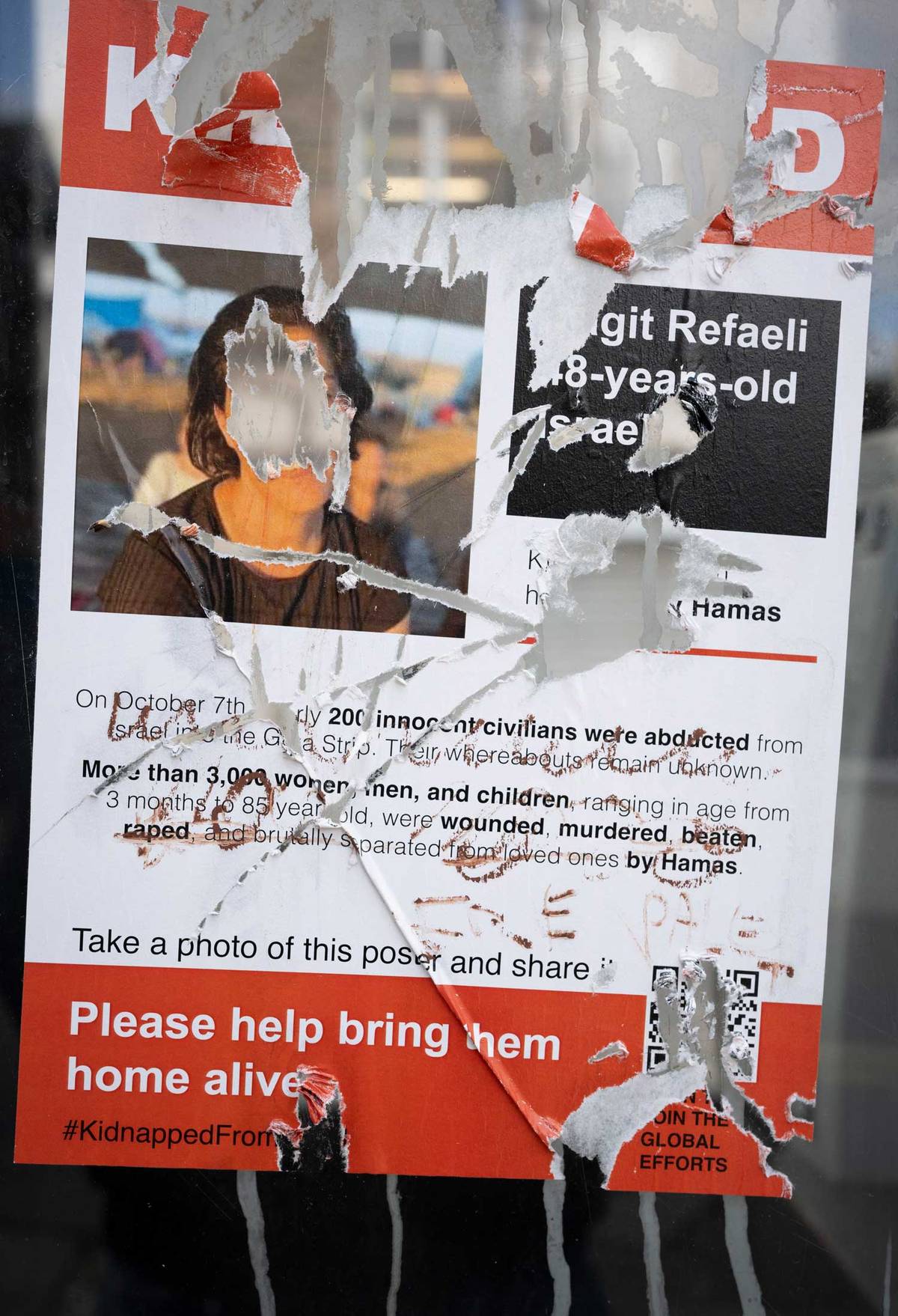 Defaced posters on a phone box window in London, November 2023
