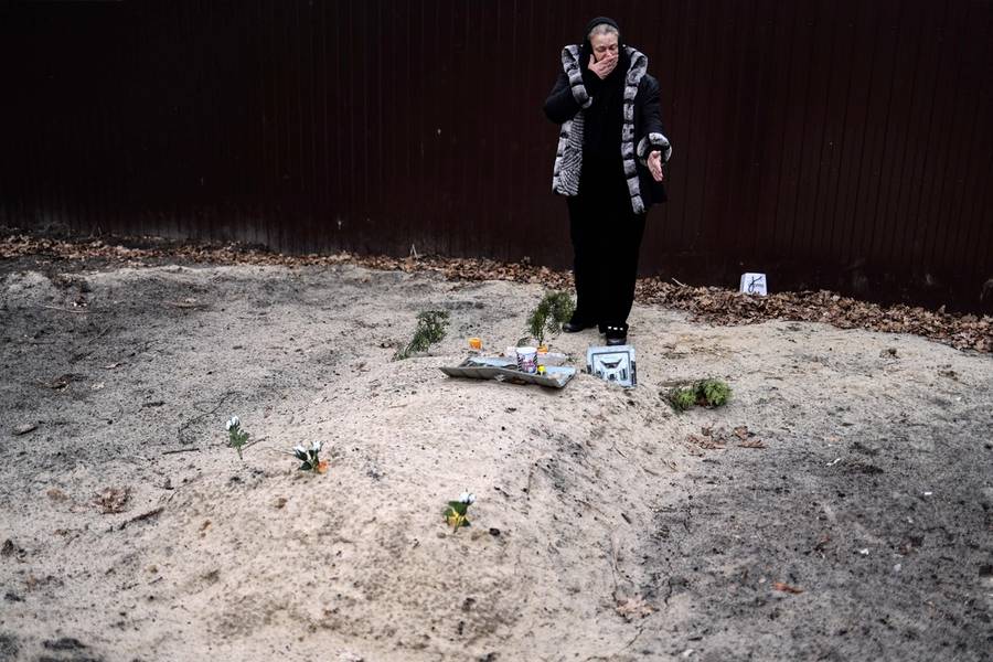 Tetiana Ustymenko weeps over the grave of her son, buried in the garden of her house in Bucha, northwest of Kyiv, on April 6, 2022
