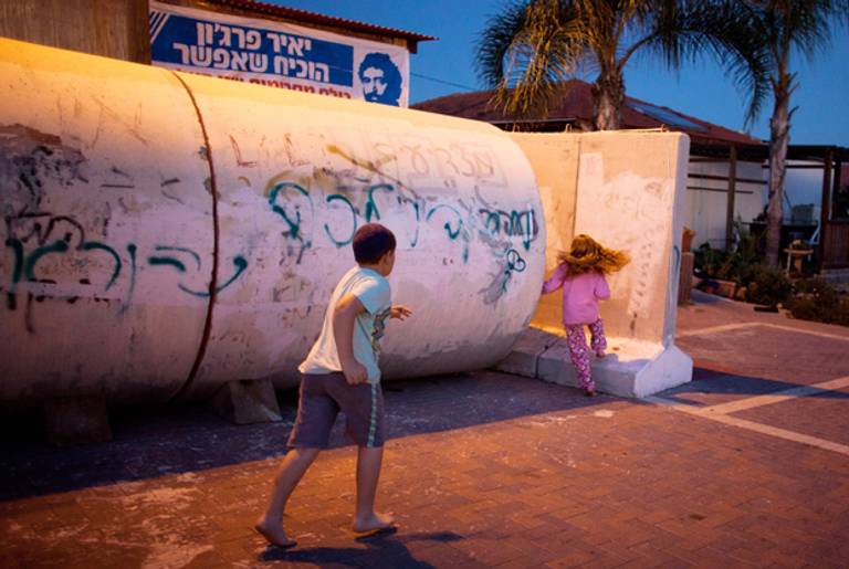 Israeli children run to a large concrete pipe used as a bomb shelter during a rocket attack from the Gaza Strip on November 15, 2012 in Nitzan, Israel. (Uriel Sinai/Getty Images)