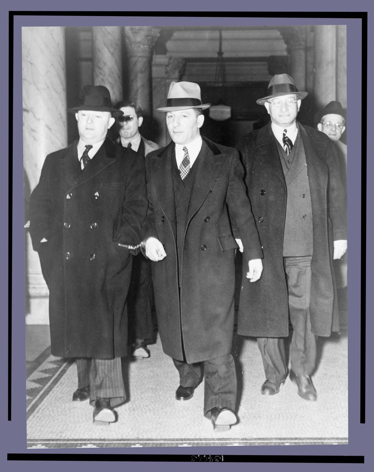 Louis ‘Lepke’ Buchalter, center, handcuffed to J. Edgar Hoover, on the left, with another man on the right, at the courthouse entrance, 1939 or 1940