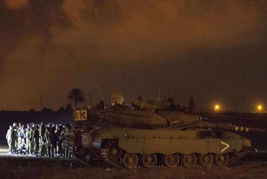 Israeli soldiers from the Golani Infantry Brigade prepare their equipment and weapons near their Armoured Personnel Carrier or APC at an army deployment near the Israeli-Gaza border,on July 19, 2014. (JACK GUEZ/AFP/Getty Image)