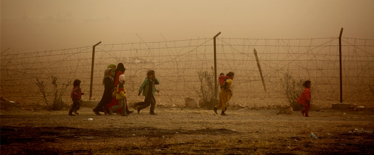 During a sandstorm, Syrian children walk around a temporary refugee camp in the village of Ain Issa in Syria, November 10, 2016. 