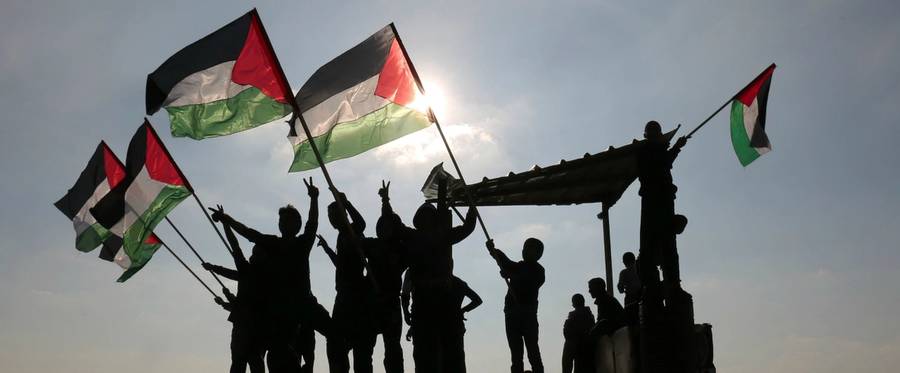 Palestinian protesters wave their national flag near the Israel-Gaza border east of the southern Gaza Strip city of Khan Yunis as they demonstrate against calls for the closure of UNRWA by the Israeli prime minister and cuts in Palestinian aid by the American president, on Jan. 9, 2018.