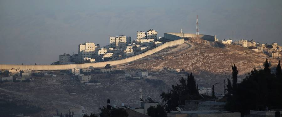 The sun sets over the Israeli separation wall on a hill separating a neighborhood of East Jerusalem (bottom) and the West Bank city of Abu Dis (top) on October 6, 2014. 
