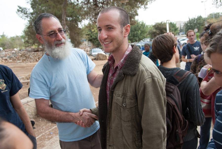 Yoav Hass, a member of Yesh Gvul, offers a supportive handshake to Moriel Rothman as he prepares to report to his draft location at Ammunition Hill, and refuse to participate in the Israeli military.(ActiveStills)