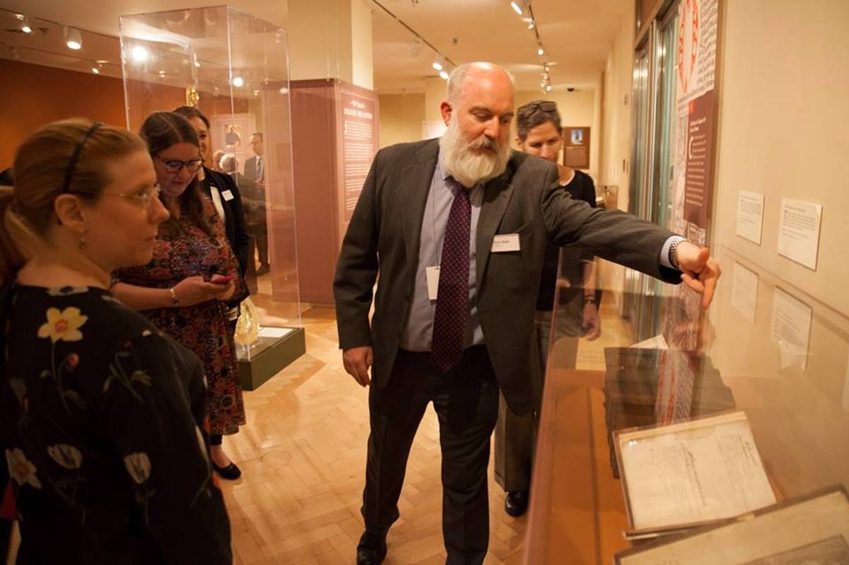 Peter Kidd, curator of “500 Years of Treasures from Oxford” exhibit, showing the 1589 Catalog of the Corpus Christi College Library to visitors. (Facebook)