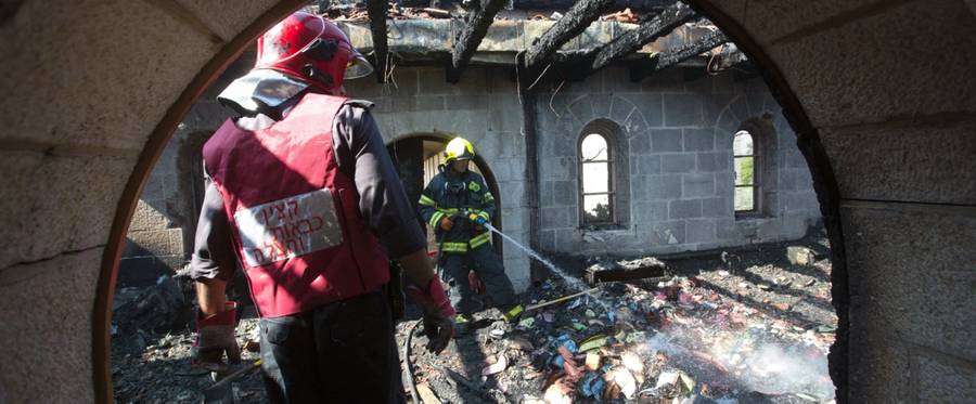 Firemen spray water on debris at a room located on the complex of the Church of the Multiplication in northern Israel, June 18, 2015. 