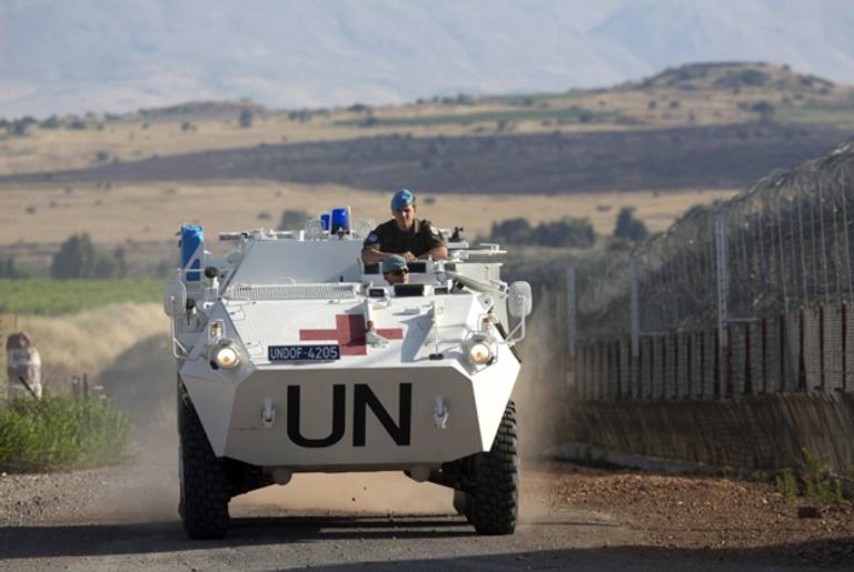 A United Nations (UN) peacekeeper vehicle make its way along the Israeli border with Syria next to the crossing of Quneitra between Syria to the Israeli annexed Golan Heights on June 12, 2013.(MENAHEM KAHANA/AFP/Getty Image)