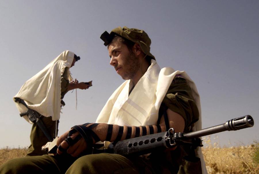 In this handout photo from the Israeli Defense Forces (IDF), ultra-Orthodox Jewish volunteers to the IDF's Nahal Haredi brigade wear prayer shawls as they recite their morning prayers during survival training at an unidentified base June 23, 2005 (Abir Sultan/IDF via Getty Images)