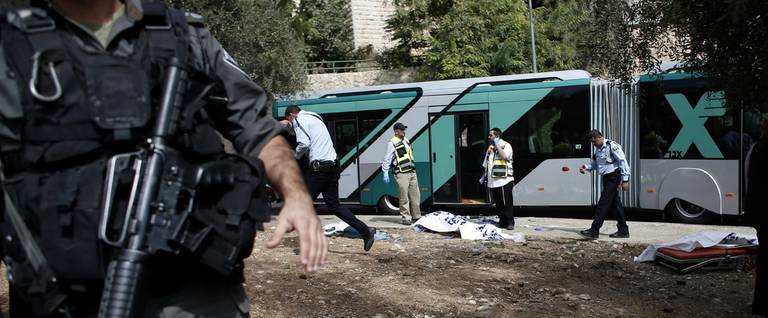 Israeli police and Zaka volunteers stand next to a body following a Palestinian shooting attack on a bus in the east Jerusalem Jewish settlement of Armon Hanatsiv, adjacent to the Palestinian neighbourhood of Jabal Mukaber, October 13, 2015. 