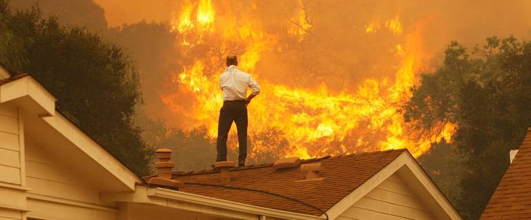 A man on a rooftop looks at approaching flames as the Springs Fire continues to grow on May 3, 2013, near Camarillo, California.