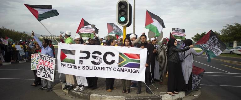 People hold Palestinian flags and a banner reading 'Palestine Solidarity Campaign' during a protest against Grammy-winning American musician Pharrell Williams near the Grand west Casino where he was holding a concert in Cape Town, South Africa, September 21, 2015. 