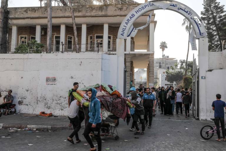 Palestinians carry usable items from a damaged Al-Ahli Hospital building after a bombing in Gaza City, on Oct. 18, 2023