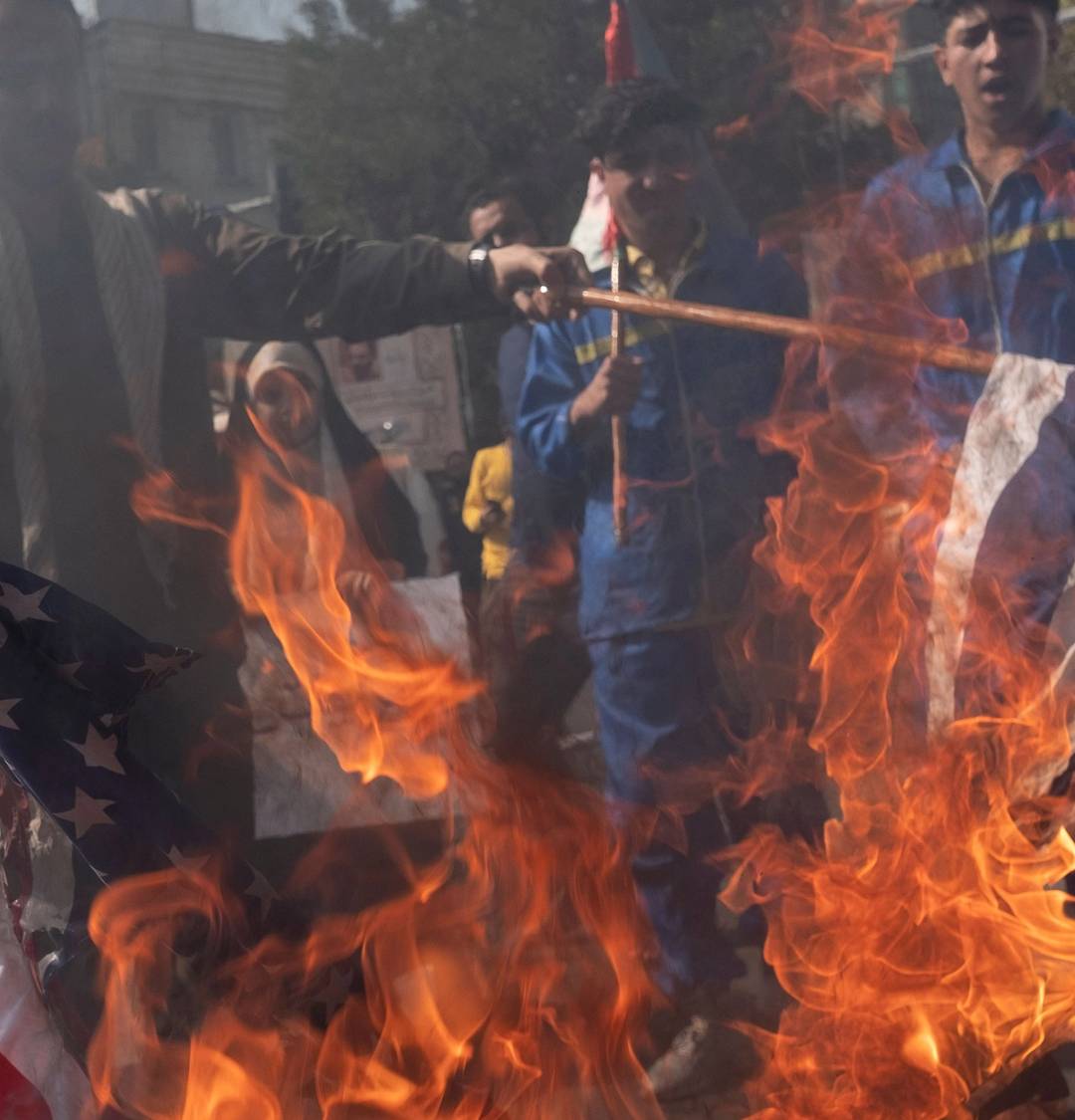 An Iranian protester wearing a military uniform burns the U.S. and Israeli flags during an anti-Israel rally in Tehran on Oct. 20, 2023