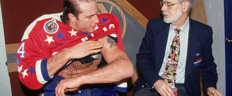 Al Iafrate, of the early-1990s Washington Capitals, shows off his bicep tattoo to analyst Stan Fischler, while Fischler holds the player's cigarette and can of soda, January 1993.