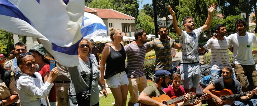 Israeli passers-by sing as they gather near the restaurant targeted during a shooting attack the previous night at a shopping complex in Tel Aviv on June 9, 2016.