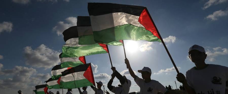 Palestinians hold their national flag on April 10, 2018 at the site of protests on the Israel-Gaza border east of Jabalia in the northern Gaza Strip.