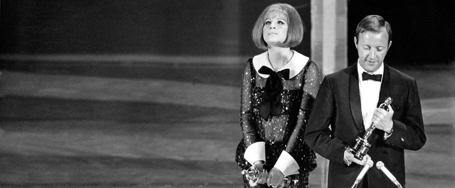 Best actress Oscar winner Barbra Streisand stands beside British director Anthony Harvey, who accepts the best actress award on behalf of Katharine Hepburn, at the Academy Awards in Hollywood, April 14, 1969. (Streisand and Hepburn were both winners in the category that year.)