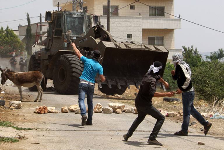 Palestinian protesters throw stones towards an Israeli bulldozer on May 24, 2013 in the village of Kafr Qaddum in the West Bank(JAAFAR ASHTIYEH/AFP/Getty Images)